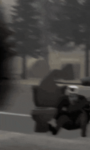 a blurry photo of a person walking down a street with trees in the background