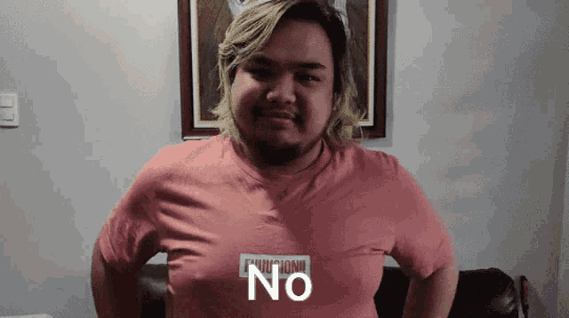 a man wearing a pink shirt that says " no " on it
