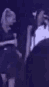 a man and a woman are standing next to each other on a stage in a dark room .
