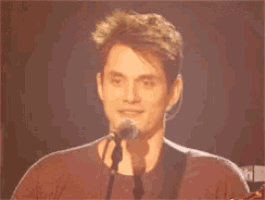 a man is singing into a microphone while holding a guitar .