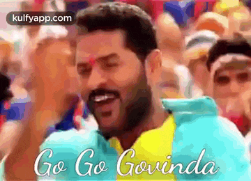 a man with a beard is dancing in front of a crowd while wearing a blue and yellow shirt .