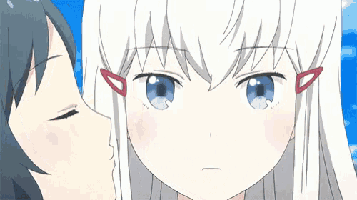 a girl with white hair and blue eyes is kissing another girl on the forehead .