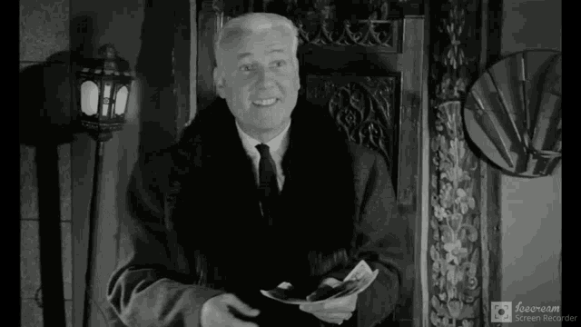 a man in a fur coat and tie holds a piece of paper in his hand
