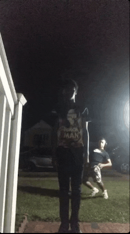 a man in a nike shirt stands in front of a house