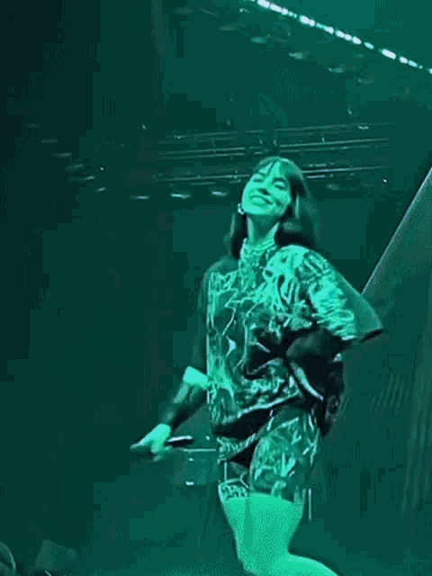 a person in a green shirt and shorts is standing on a stage .