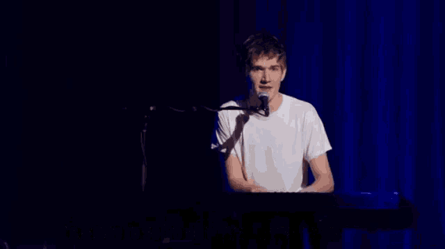 a man singing into a microphone with the words " it 's a way to solve all the sadness in the world " above him