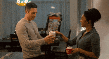 a man is giving a woman a cup of hot chocolate with whipped cream