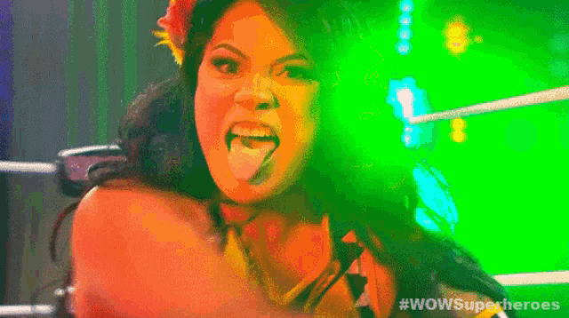 a woman sticking her tongue out in a wrestling ring with the words wowsuperheroes on the bottom right