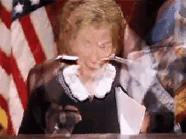 a blurry picture of a woman sitting at a table with an american flag behind her