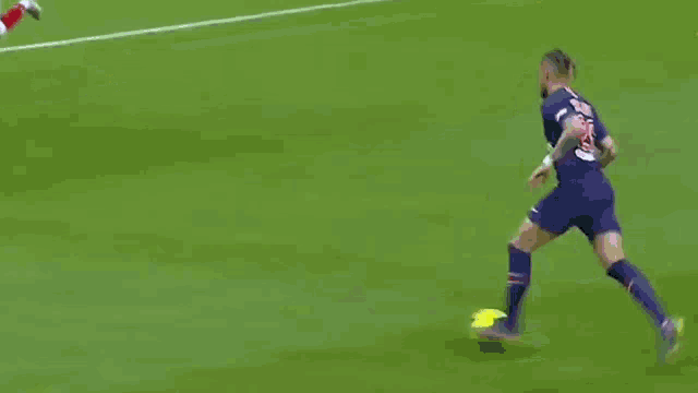 a soccer player in a red shirt is kicking a yellow ball on a soccer field .