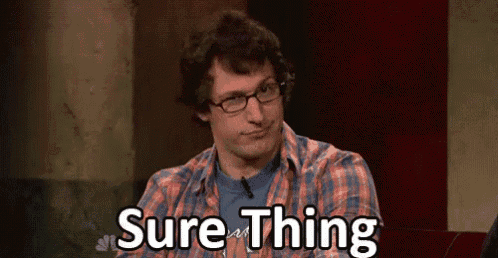 a man wearing glasses and a plaid shirt is sitting in front of a sign that says sure thing .