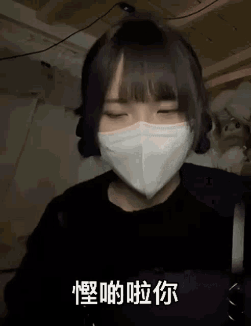 a girl wearing a mask with chinese writing on it is making a funny face .