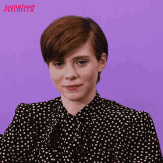 a woman wearing a black and white polka dot shirt is making a sad face