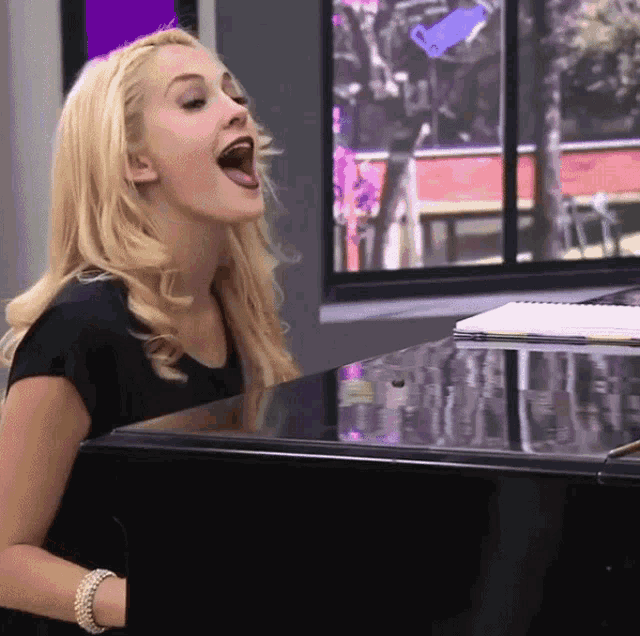 a woman singing into a microphone while playing a piano