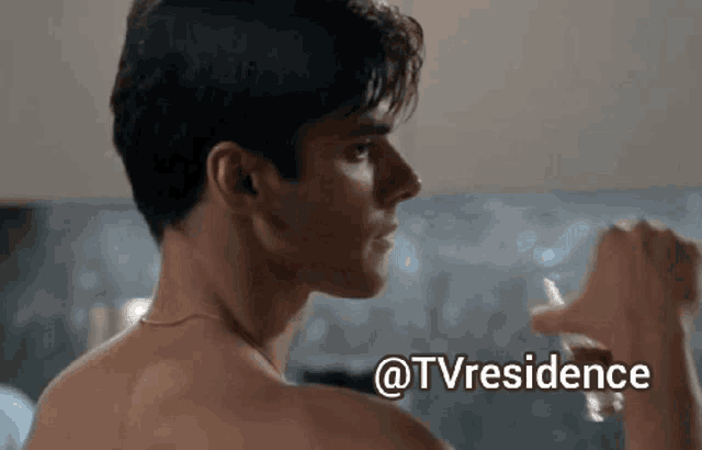 a man without a shirt is holding a glass of water in front of a tv residence logo