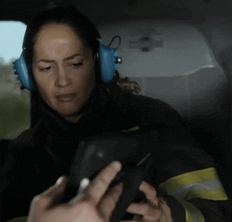 a woman wearing headphones is holding a cell phone in her hands .