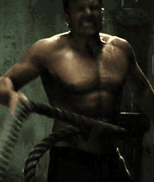 a shirtless man is holding a rope in his hand