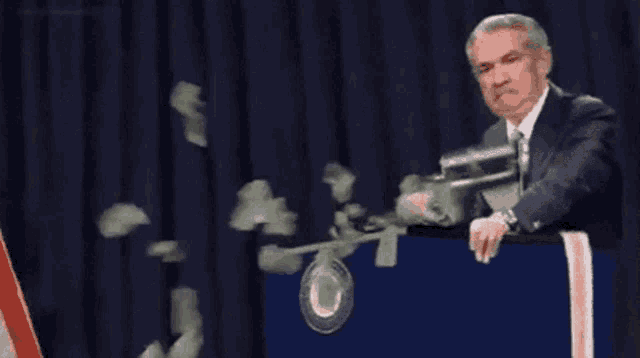 a man in a suit and tie is holding a gun and money is falling around him