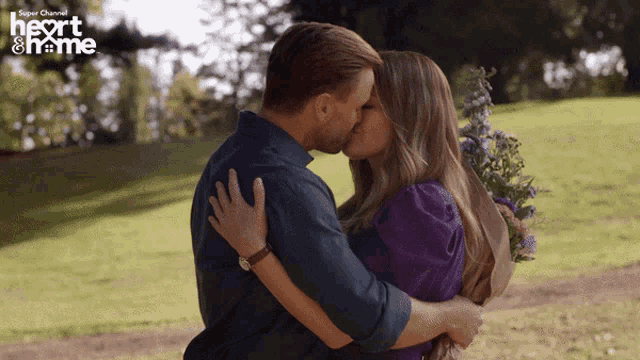 a man and woman kissing in front of a sign that says " heart & home "