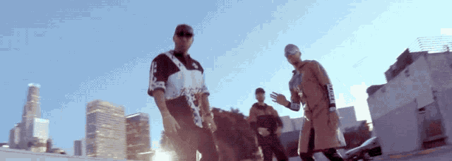 a group of men are standing in front of a city skyline and one of them is wearing a shirt that says supreme on it