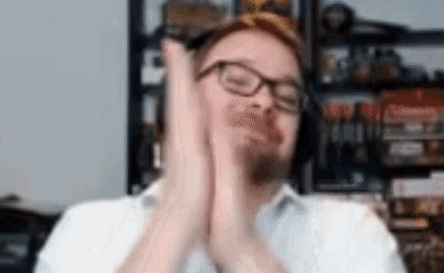 a man wearing glasses and headphones is clapping his hands in a blurry photo .