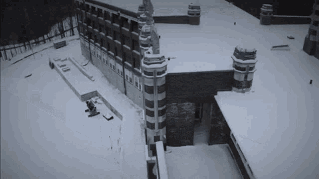 an aerial view of a snow covered building with a tower on the roof