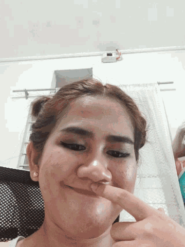 a woman is making a funny face with her finger on her nose