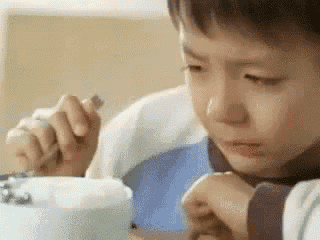 a young boy is eating a bowl of food with a fork and knife .