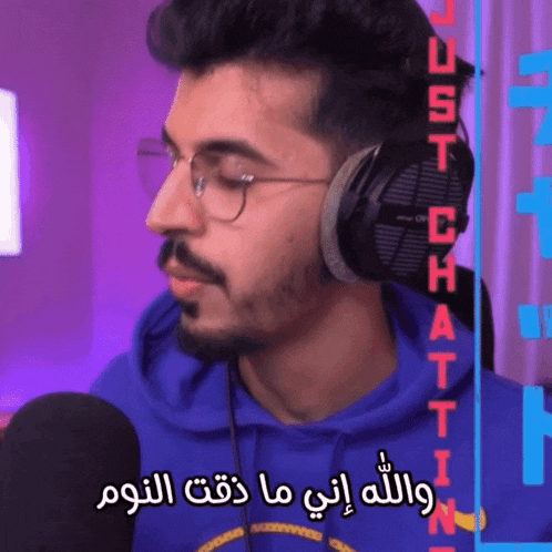 a man wearing headphones and a blue hoodie says just chattin in arabic