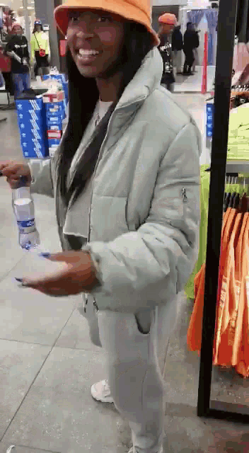 a woman in an orange hat is holding a bottle of water in her hand