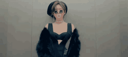 a woman in a black dress , fur coat , sunglasses and a hat is standing in an elevator .