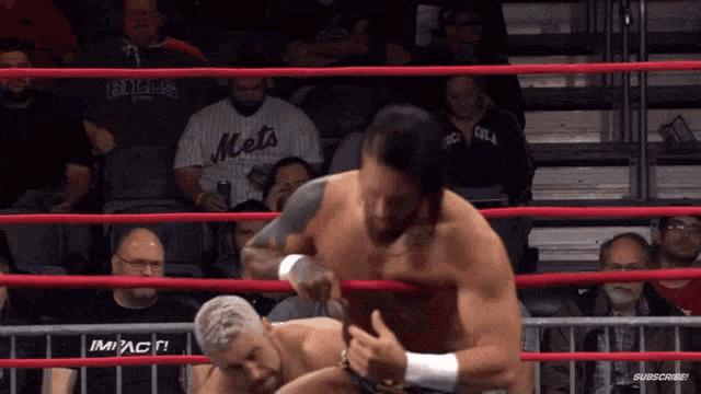 a man in a mets shirt is wrestling another man in a ring