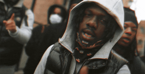 a man wearing a white hoodie and a black vest has a bandana around his neck that says adidas