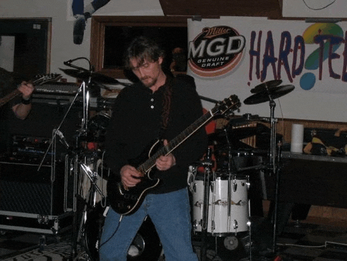 a man is playing a guitar in front of a sign that says mgd