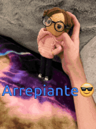 a person is holding a crocheted doll with glasses and the word arrepiante written in blue
