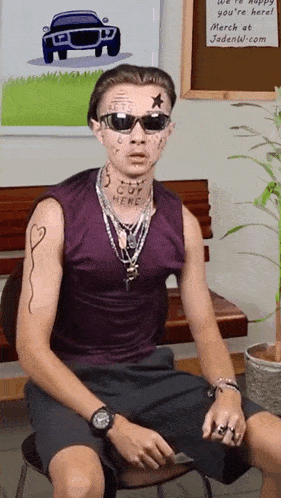 a man wearing sunglasses and a purple shirt has a tattoo on his face that says " cut here "