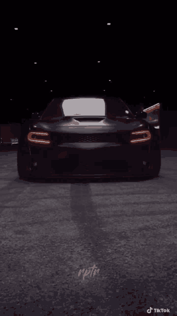 a black car is parked in a dark parking lot with tiktok written on the bottom right corner