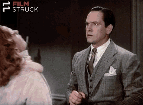a man in a suit and tie stands in front of a woman with film struck written in the corner