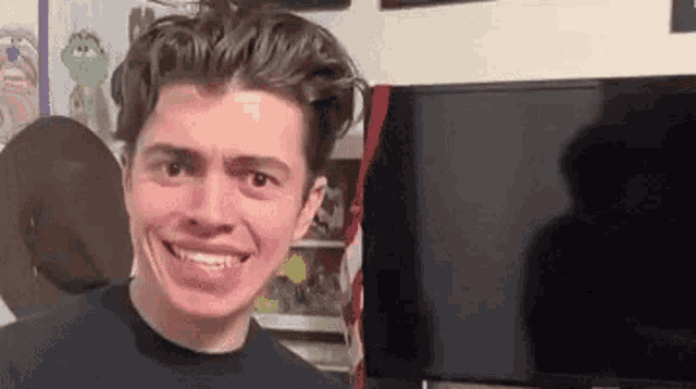 a young man is making a funny face while standing in front of a television .