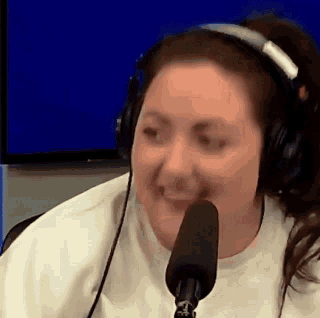 a woman wearing headphones is talking into a microphone and smiling