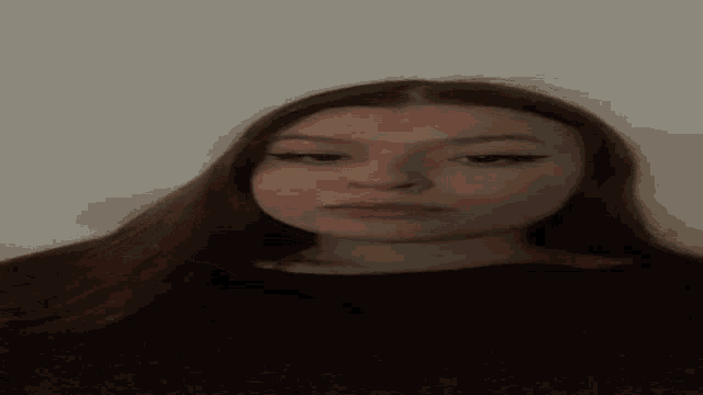 a woman with long hair is taking a selfie with her head down .