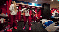 a group of people are dancing in a locker room and one of them is wearing a white shirt with the number 11 on it