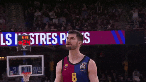 a basketball player wearing a number 8 jersey stands in front of a scoreboard