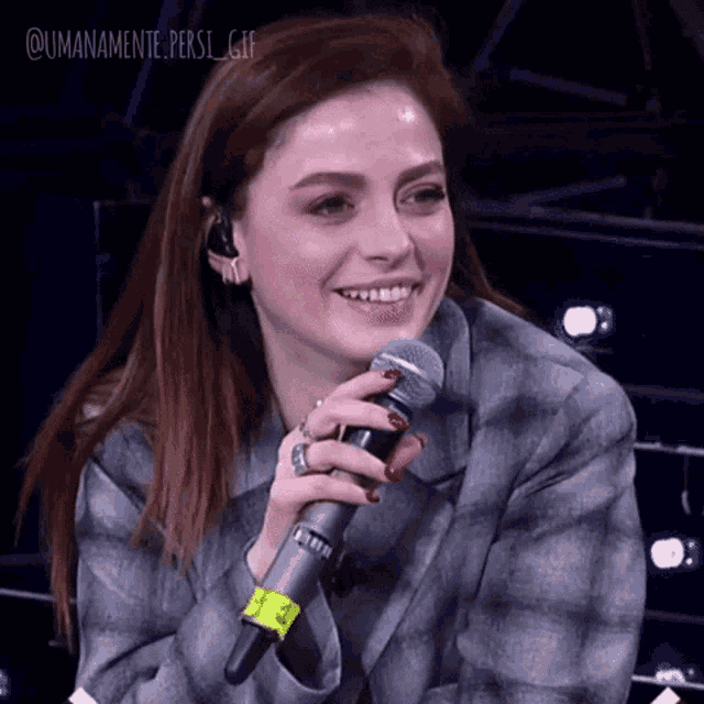 a woman is smiling while holding a microphone with the hashtag umanamente persi gif written on the bottom