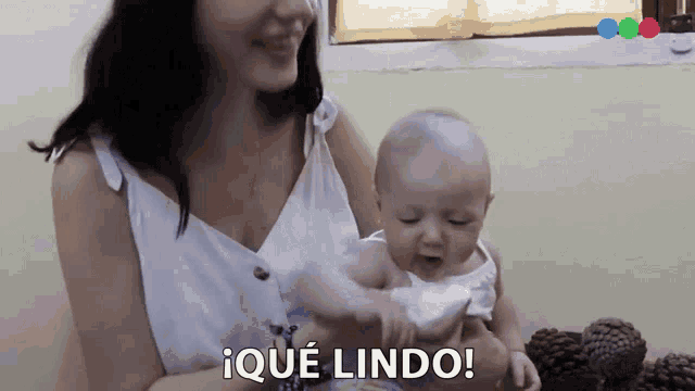 a woman is holding a baby in her arms and the baby is saying " ique lindo "
