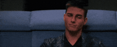 a man in a leather jacket is sitting in front of the word rela