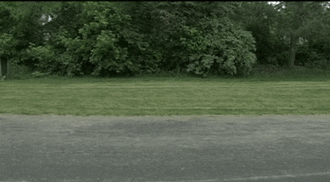 a man in a gray shirt and red shorts is running down a road .