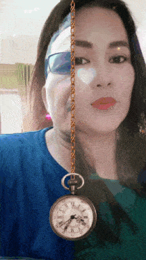 a woman 's face is behind a pocket watch with roman numerals on it