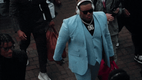 a man wearing a suit and headphones has the number 96 on his shirt