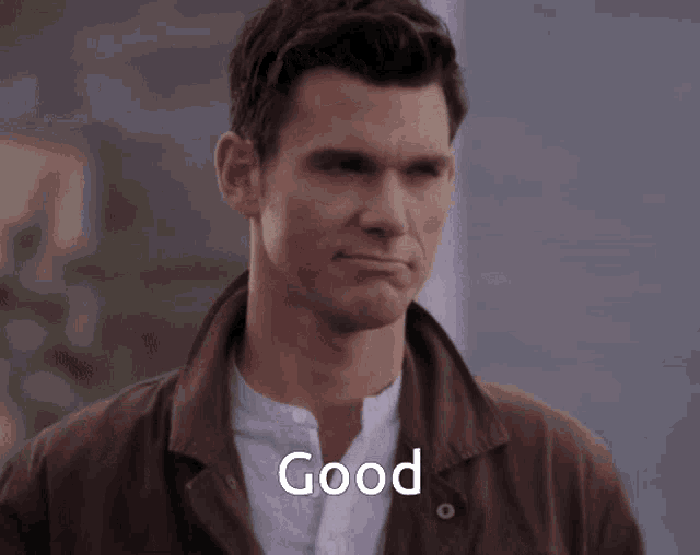 a man wearing a brown jacket and a white shirt says " good "